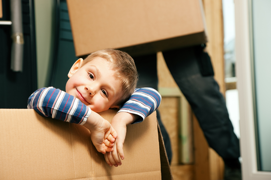 little boy playing in a brown cardboard box