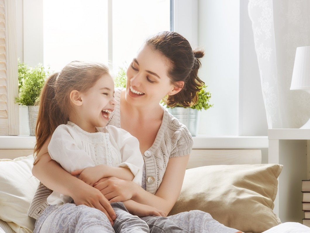 mother laughing with her daughter in her lap